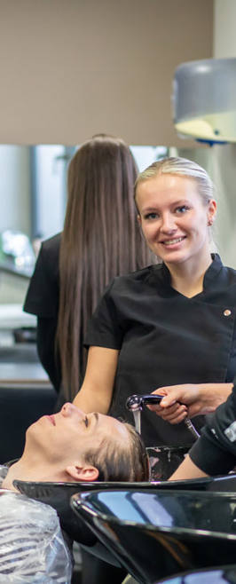 Hairdressing Lecturer and student washing client's hair in salon